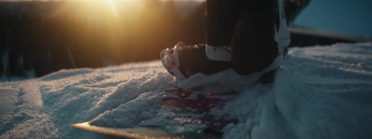 A person is adjusting the straps on their boots and snowboard