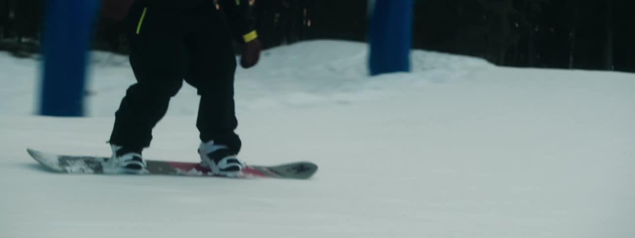 A snowboarder snowboards over a snowy ramp on a slope during the day