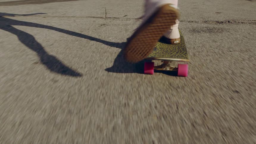 A person is riding a skateboard near a parking lot