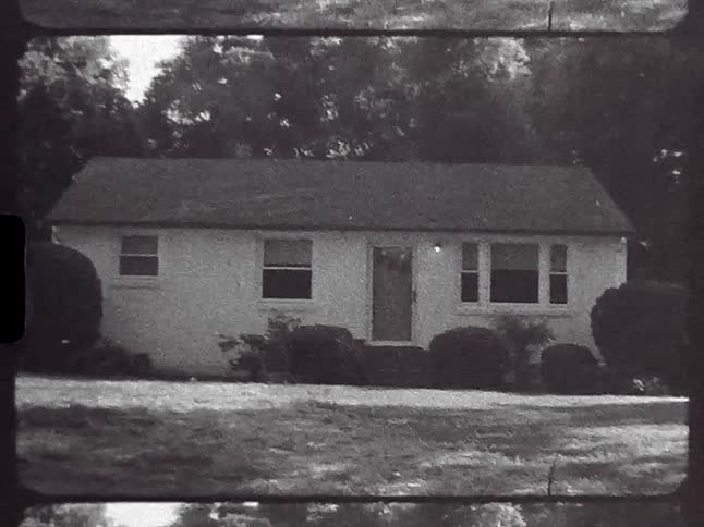 A small house is shown on old black and white film