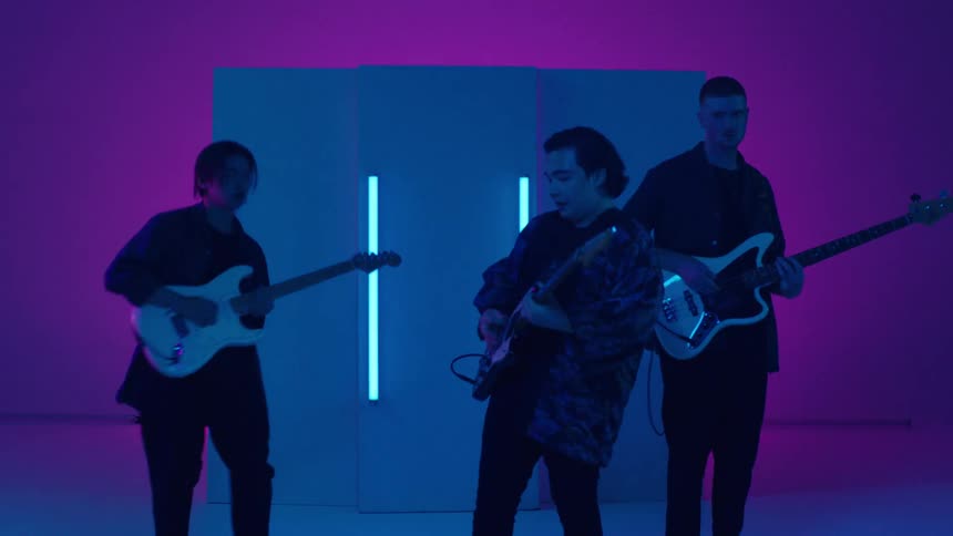 A man playing the guitar sings while two other men play guitar