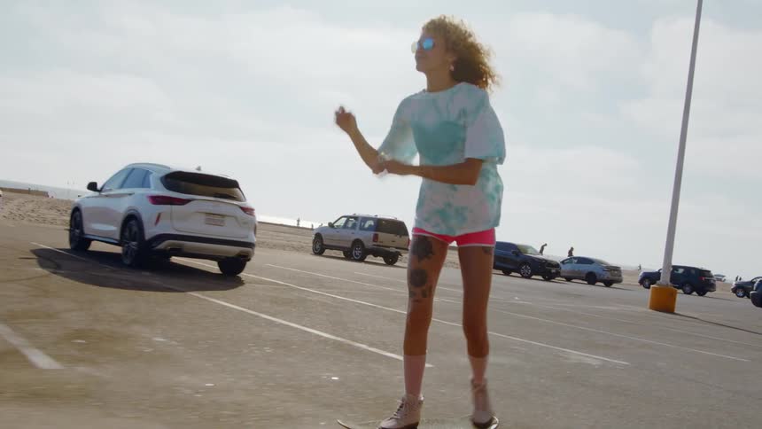 A woman is skateboarding outdoors in a parking lot