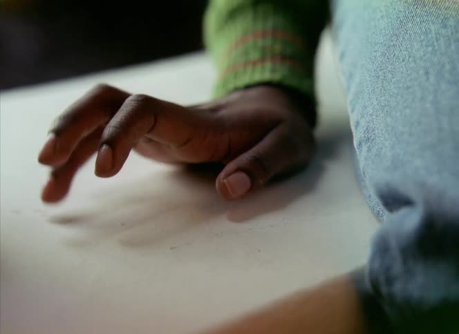 A person taps their fingers idly while sitting on a bench