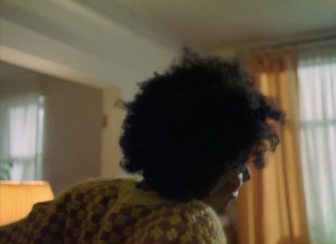 Close up of the face of a young woman with an afro dancing by herself in the living room at home