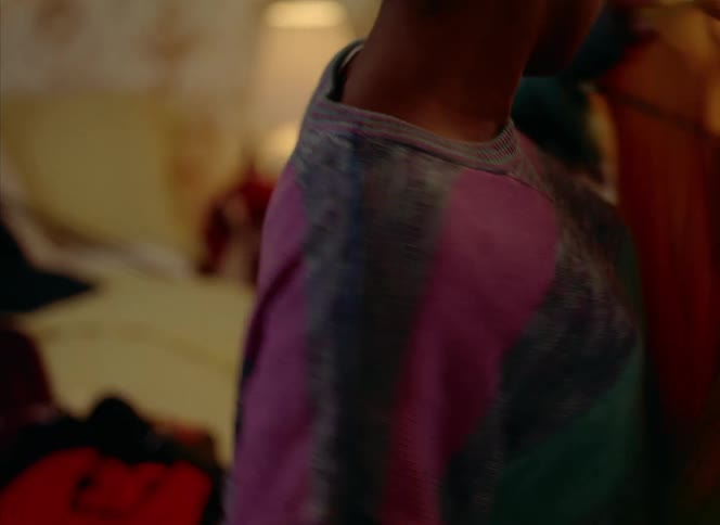 A woman is picking up different clothes and holding them against herself