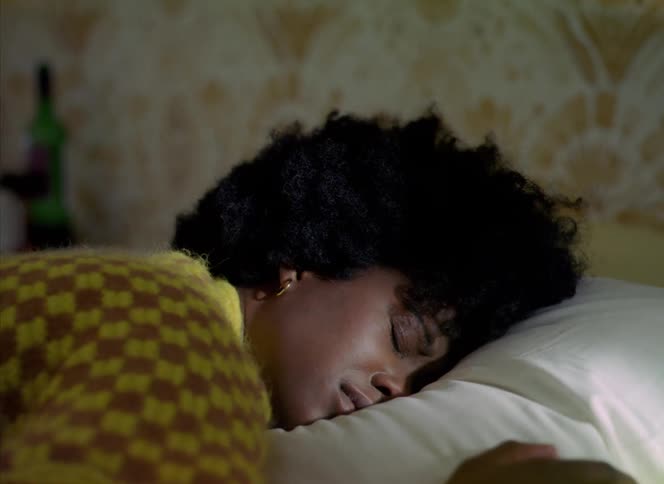 A woman is sleeping in bed then wakes up and rolls over