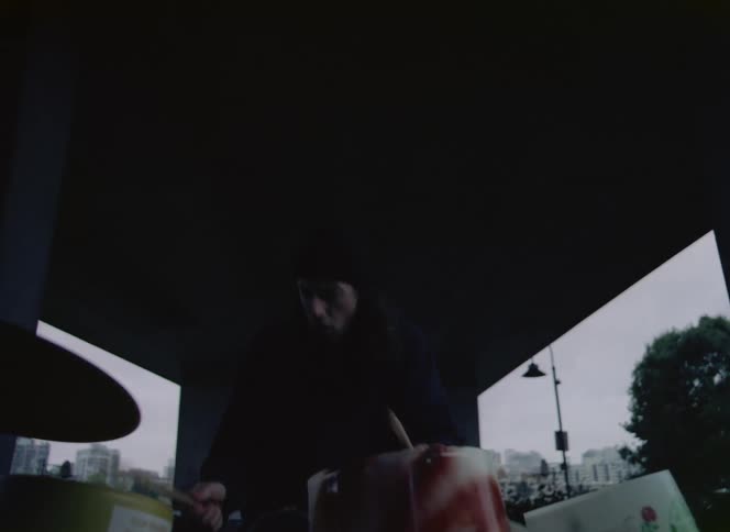 A man is outdoors and playing the drums instrument