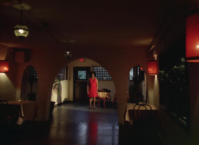 A woman standing inside an empty restaurant touching a table then walking away