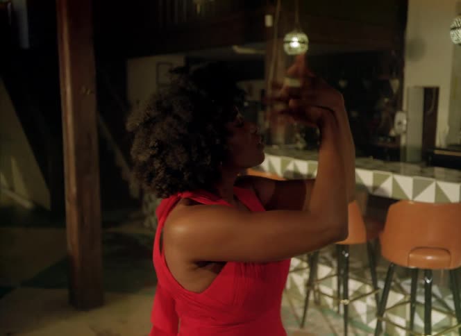 A woman dances in front of a bar counter