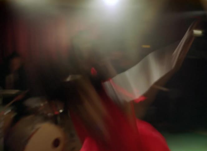A light shines on a woman dancing in front of a band of musicians