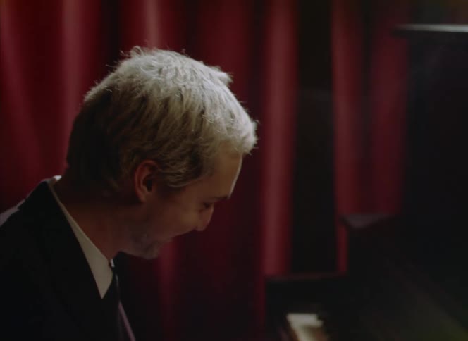 A man smiles as he plays the piano