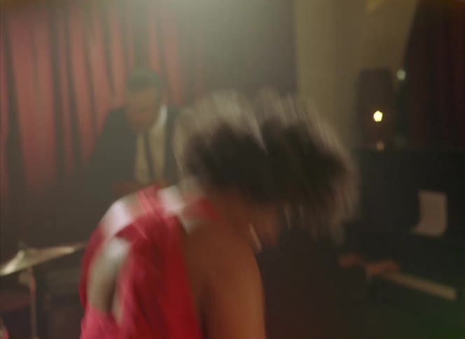A woman dances wildly in front of a band playing