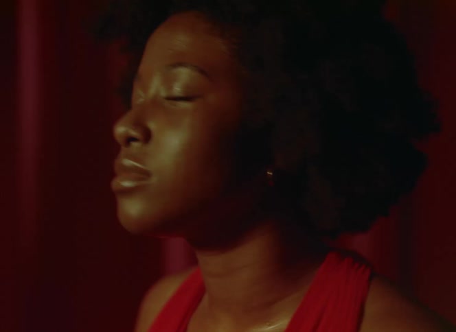 Light shines on the face of a woman as she sweats as she dances