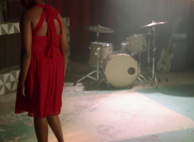 A woman is walking around a room with musical instruments