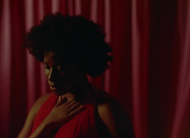 A woman in a red dress dances in front of a red curtain