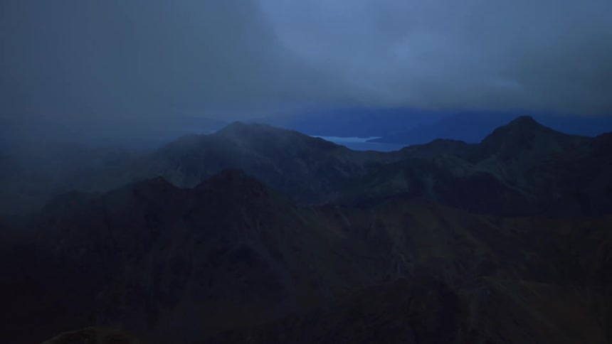 Clouds floating above a mountain range at night