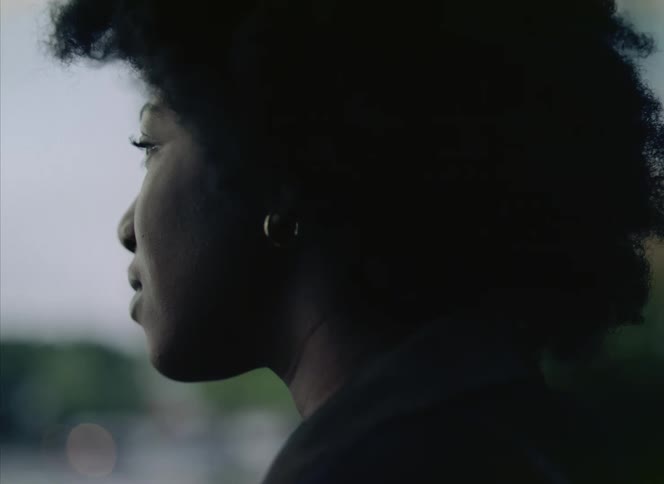 Back of womans head with curly hair and earrings smiling