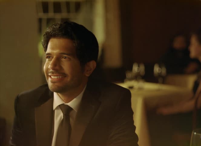 Young happy man smiles and laughs while sitting at a table in a restaurant