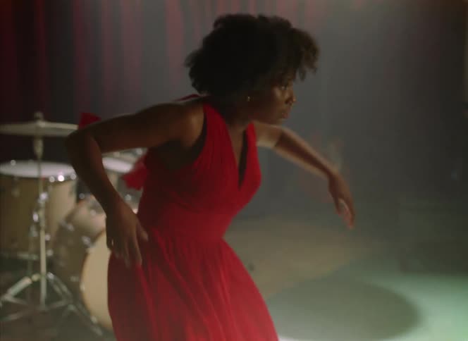 A woman dances in front of a drum set