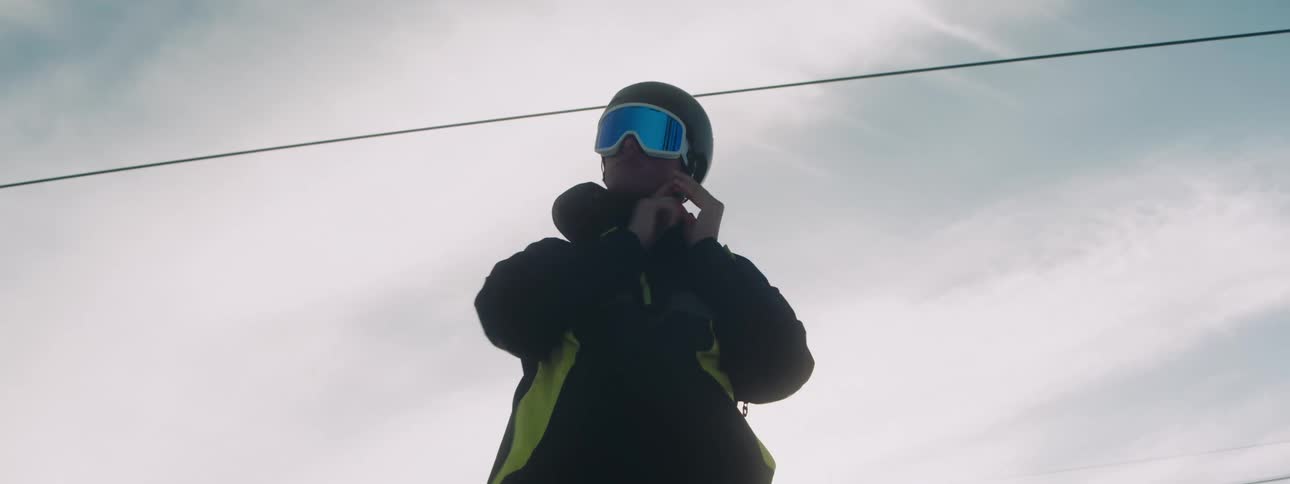 Man puts on snowboard equipment in snowboarding resort