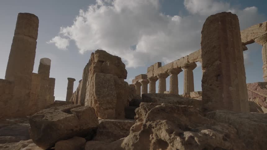 Clouds float over pillars and ruins on a sunny day