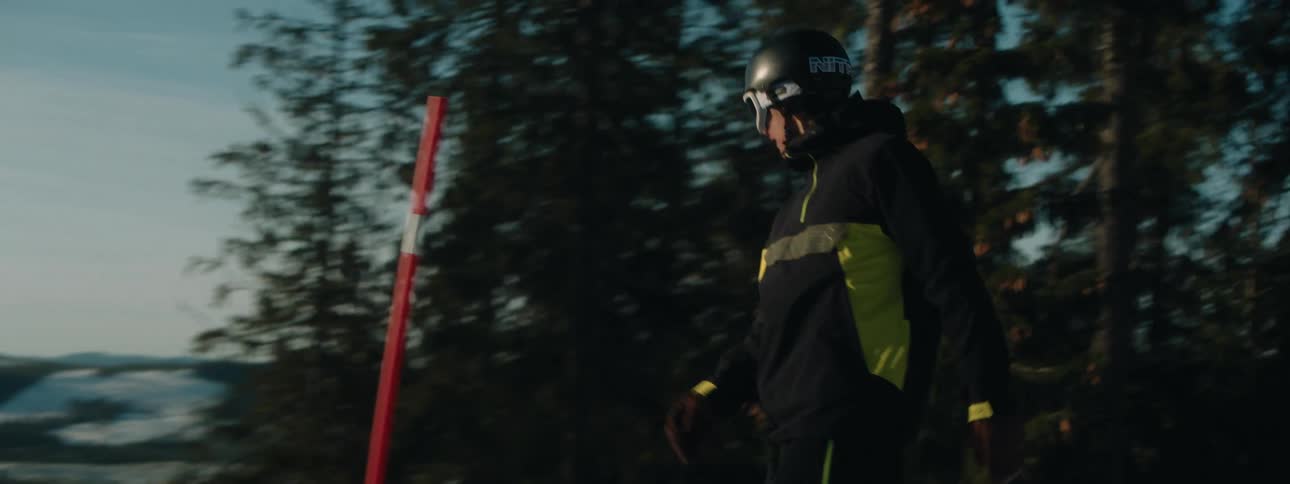 A snowboarder going down a mountain slows to a complete stop overlooking the slope