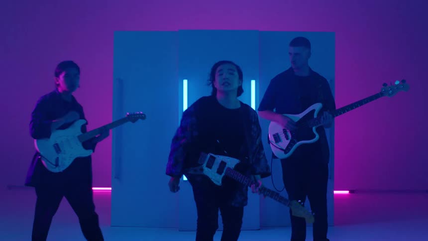 Small group of musicians plays guitar and and singing on stage with purple lights