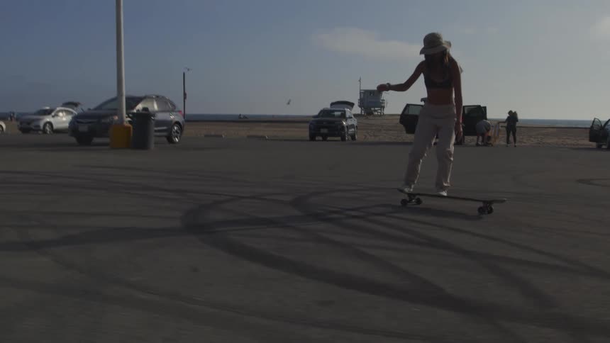 A woman is skateboarding outdoors in a parking lot