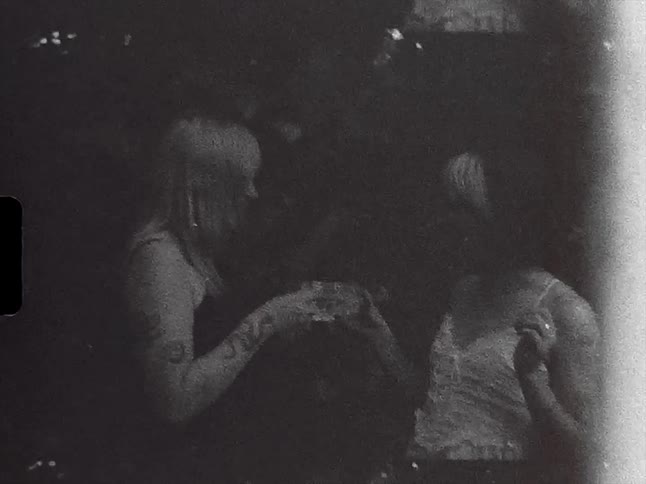 Two women clink their mugs and take a drink while hanging out in a backyard