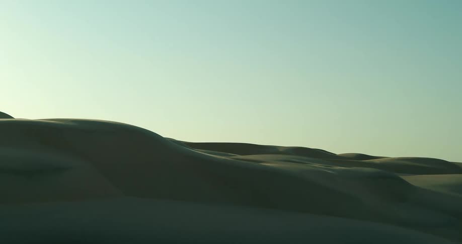 Sunlight shines on desert sand dunes under a clear sky