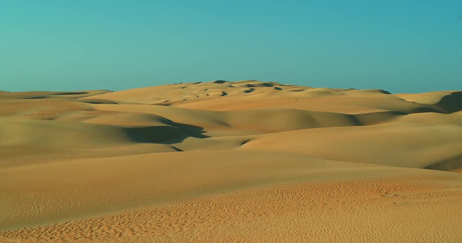 Aerial view of desert with sand dunes under blue sky