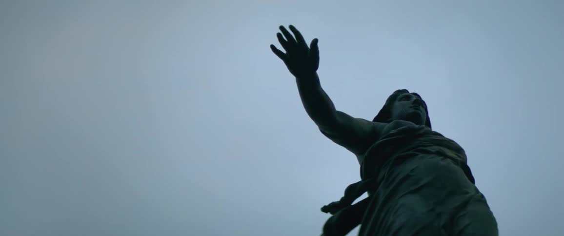 A large statue features a man holding out his arm