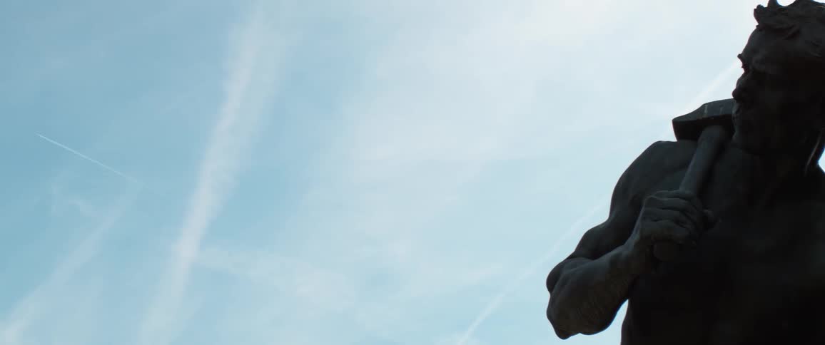 A statue of man carrying a hammer on his shoulder