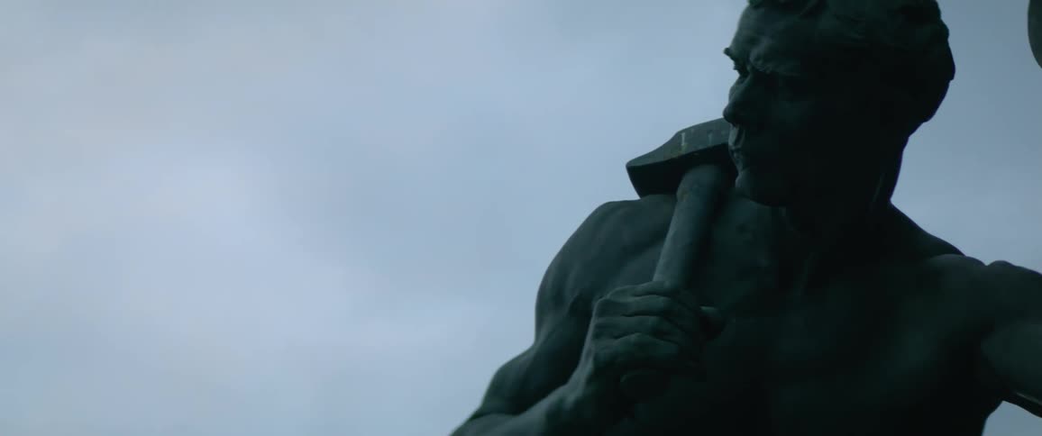 A large statue features a man holding an ax on his shoulder