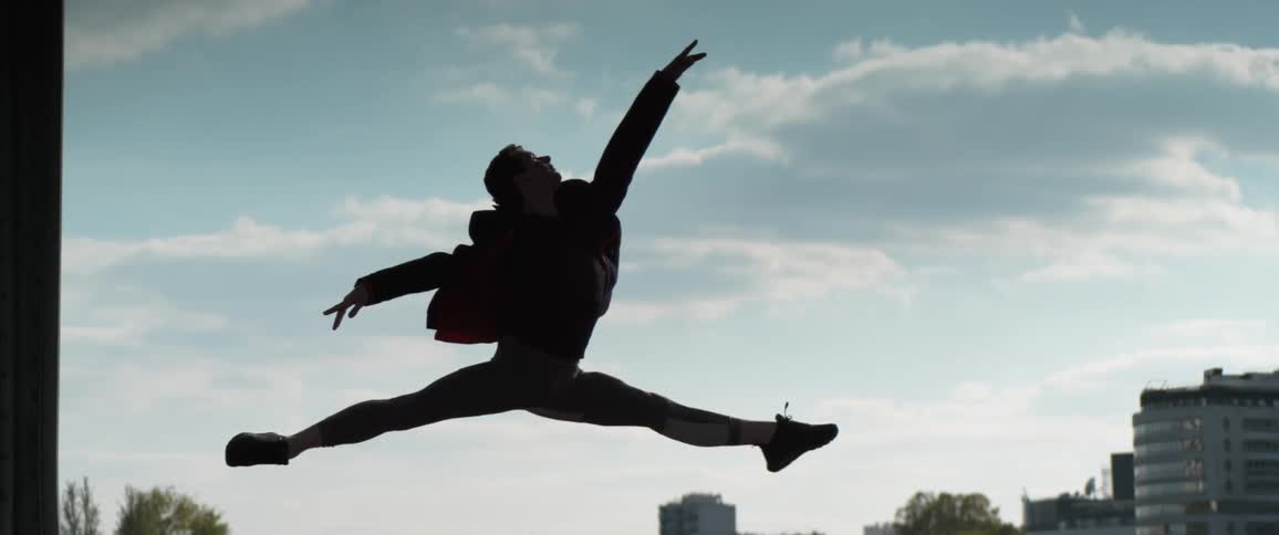 A man is doing a ballet jump in the city