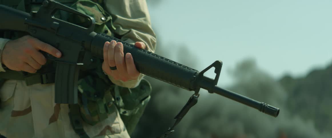 A soldier holds a rifle as the smoke rises