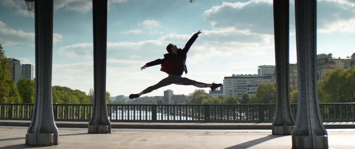 Dancer leaps high with river and city in the background