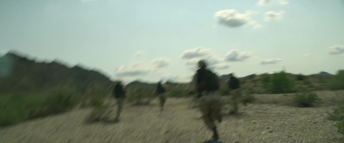 A group of soldiers in uniforms runs in the field