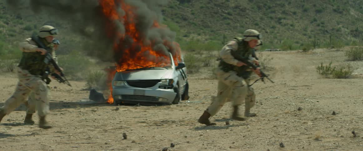 Group of soldiers on a training exercise running away from a car engulfed in flames