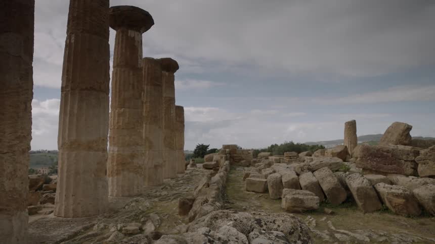 Ruins and stone pillars stand in a rural area