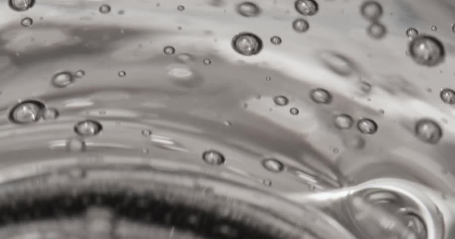 A clear viscous liquid moves in a stainless steel container