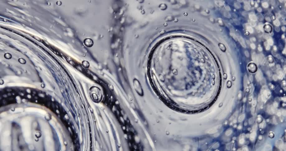 Variable sized bubbles form as concentric circles flow through translucent fluid