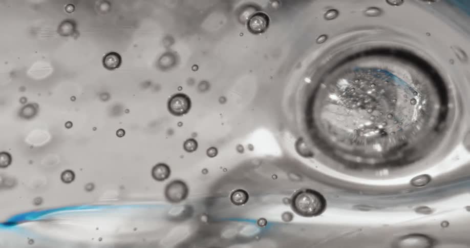 A round ice cube floats in water dyed blue