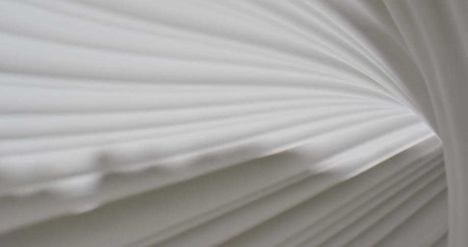 A pleated white fabric curves and reflects light and shadow