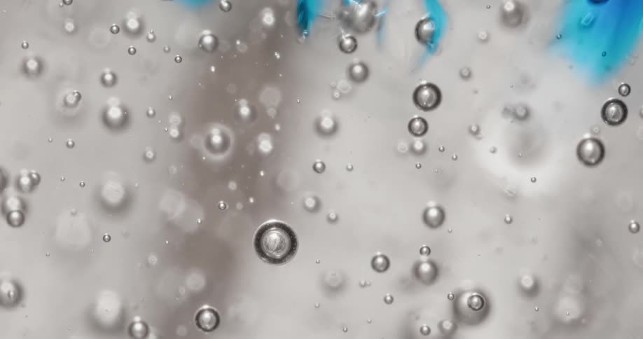 Close up of air bubbles floating up and down a blue translucent thick gel tinted with blue liquid ink