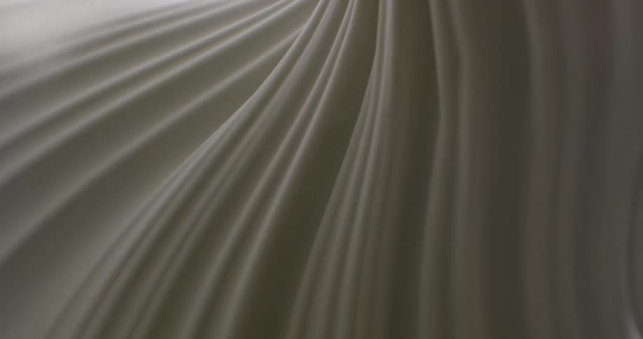 Light shines on a white textured substance and creates shadows in the grooves until it becomes dark