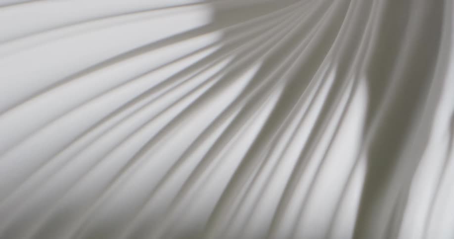 A light shines over a pleated white fabric