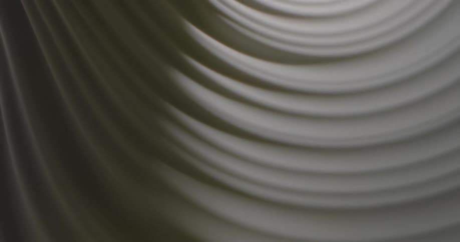 Light shines on a white textured substance as it turns and creates shadows in the grooves until it becomes dark
