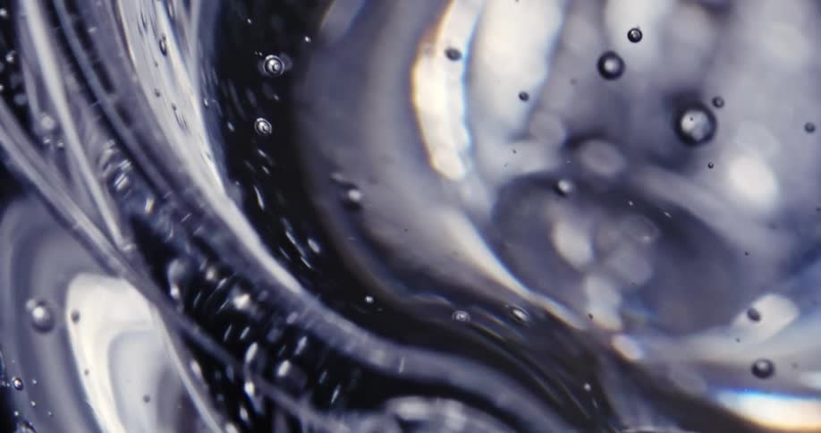 Bubbles rise to the surface as ripples move outward in a clear liquid