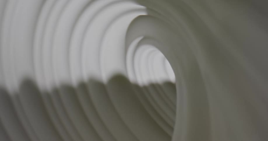 Light shines on a white swirling substance as it spins into a tunnel and becomes dark as the shadows move and grow